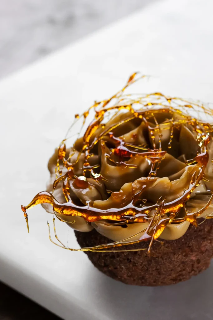 Ptyś z kremem i błyszczącym karmelem na białek desce