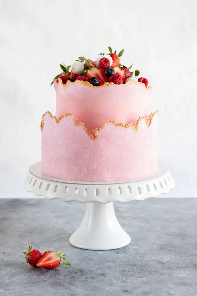 Tort piętrowy z warstwą sugar sheet i owocami na szarym tle