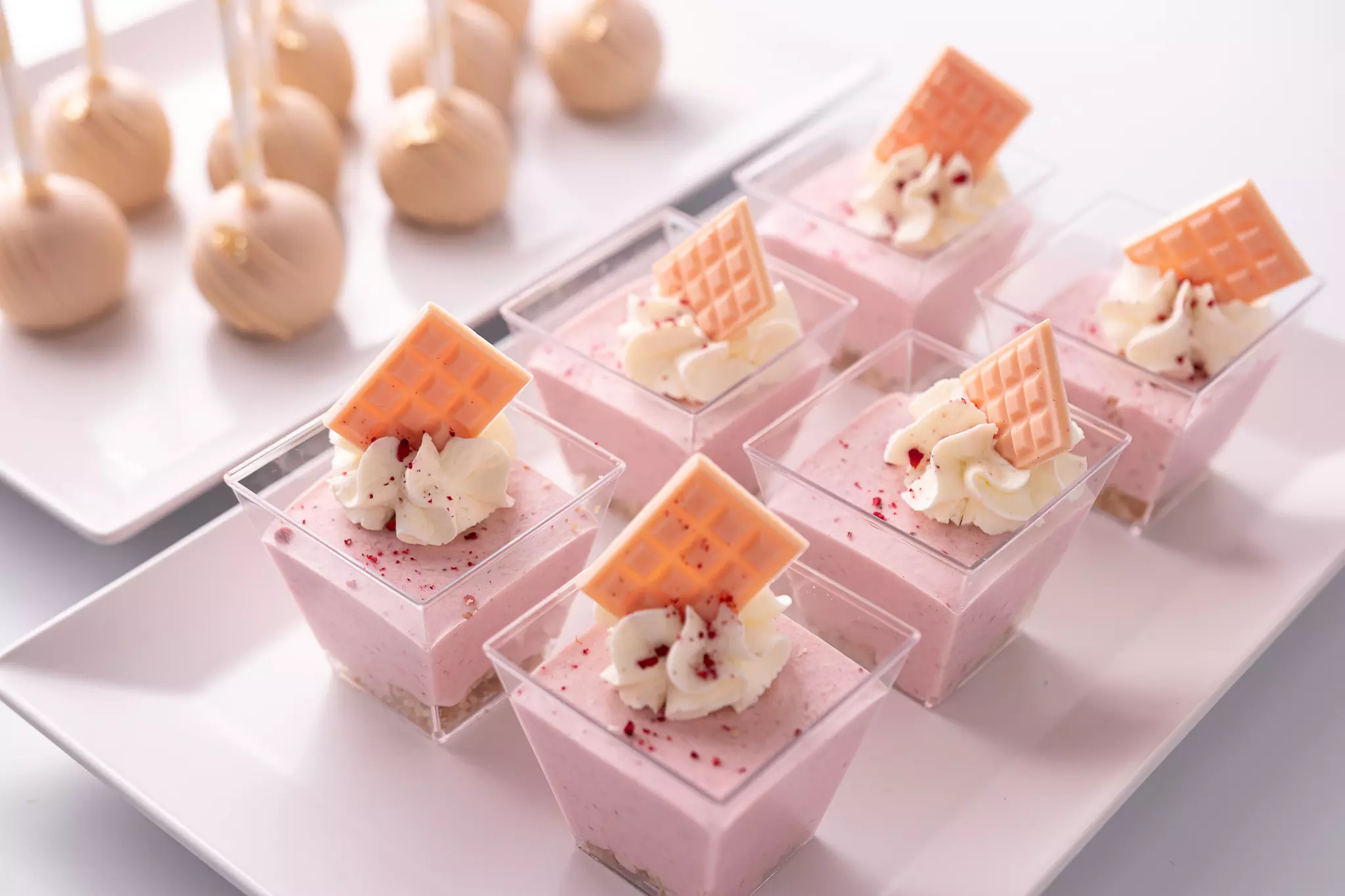 Różowy krem z bitą śmietaną i czekoladą podany w bankietówce na słodkim stole