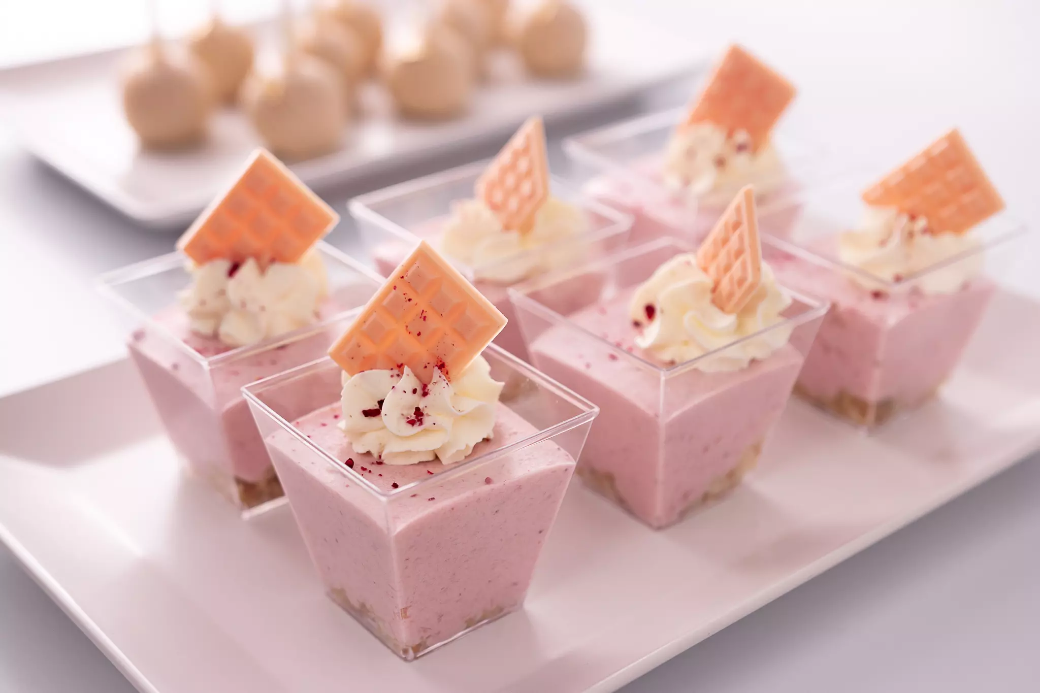 Różowy krem z bitą śmietaną i czekoladą podany w bankietówce na słodkim stole