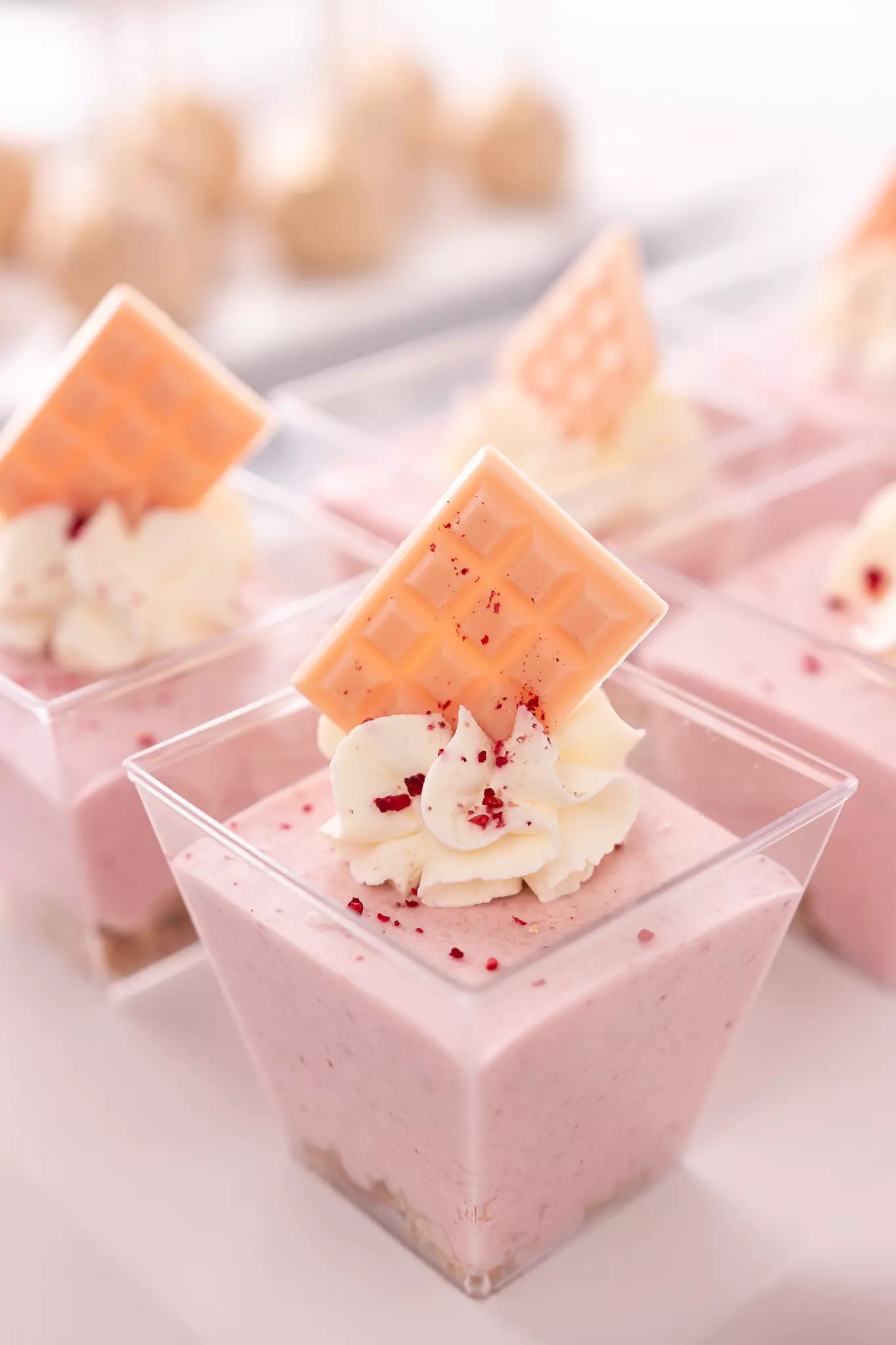 Różowy krem z bitą śmietaną i czekoladą podany w bankietówce na słodkim stole